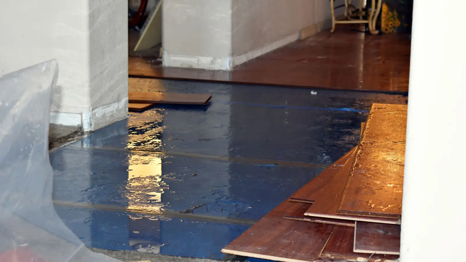 Hardwood planks lifted by water beside plastic sheeting during drying