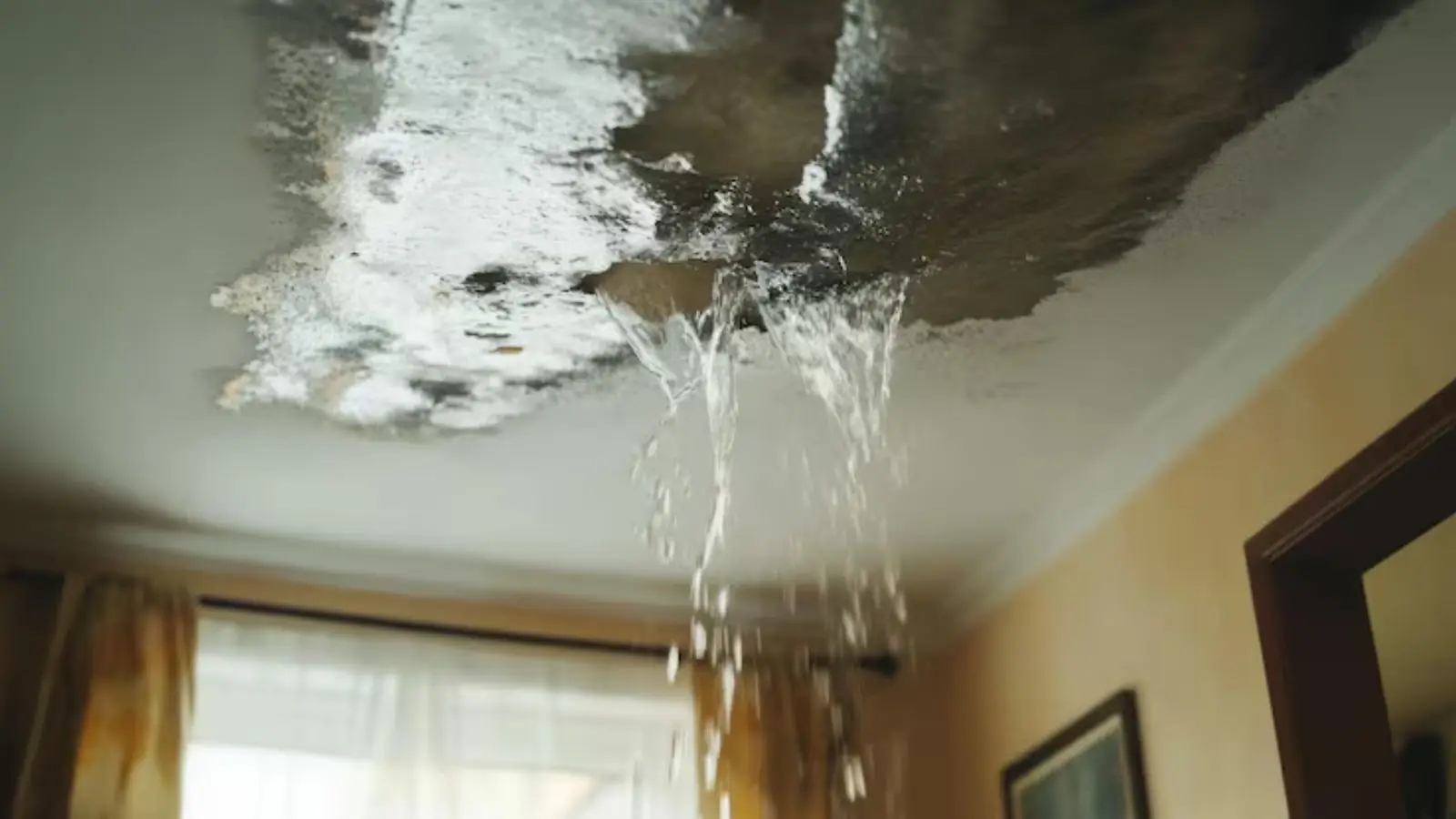 Water pouring through a damaged ceiling into a room below